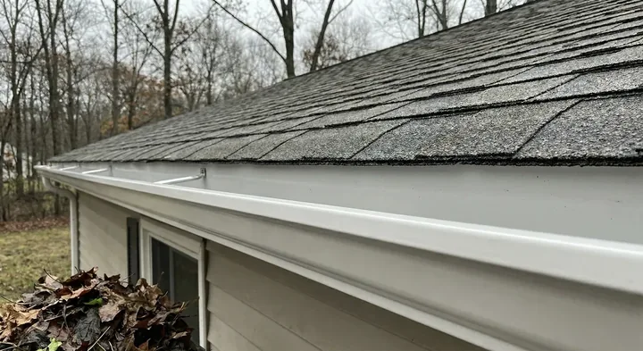 A freshly cleaned eavestrough on a GTA home, with the leaves that came out of it on the lawn below