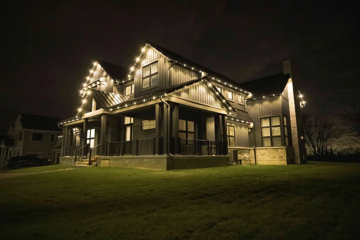 A two-storey home lit in warm white along the roofline and peaks