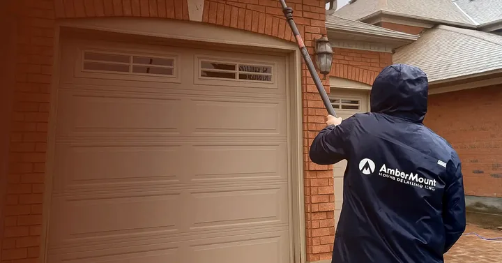 AmberMount crew member cleaning the windows above a garage with a water-fed pole